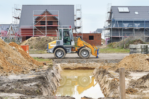 Baufahrzeug auf einer Baustelle eines Neubaugebietes mit Einfamilienhäusern