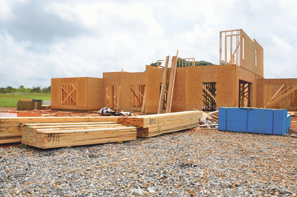 Holz vor dem Rohbau eines halb-fertigen Holzhauses