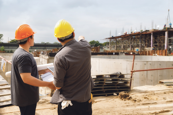 Zwei Männer mit Helmen betrachten eine Baustelle